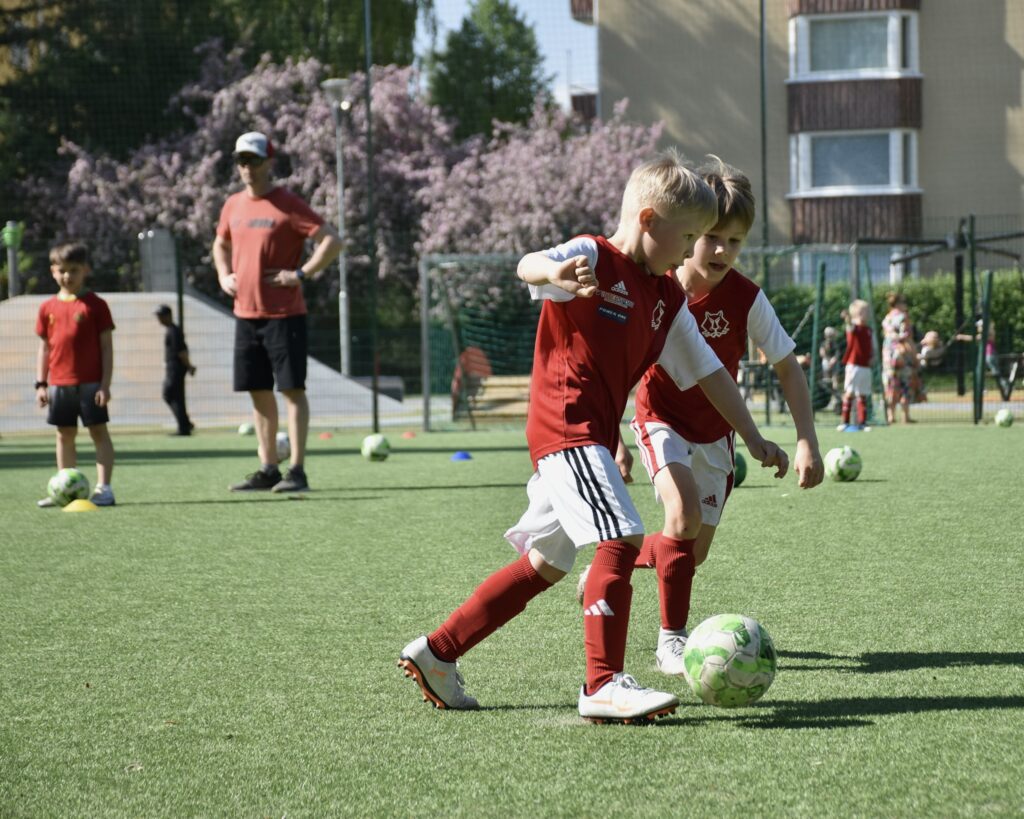 lapset pelaavat jalkapalloa kentällä