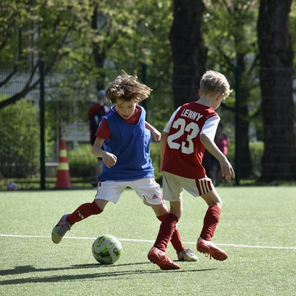 kaksi nuorta jalkapallopelaajaa kamppailee pallosta