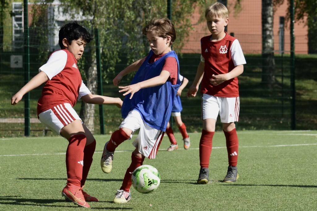 lapset kentällä pelaamassa jalkapalloa