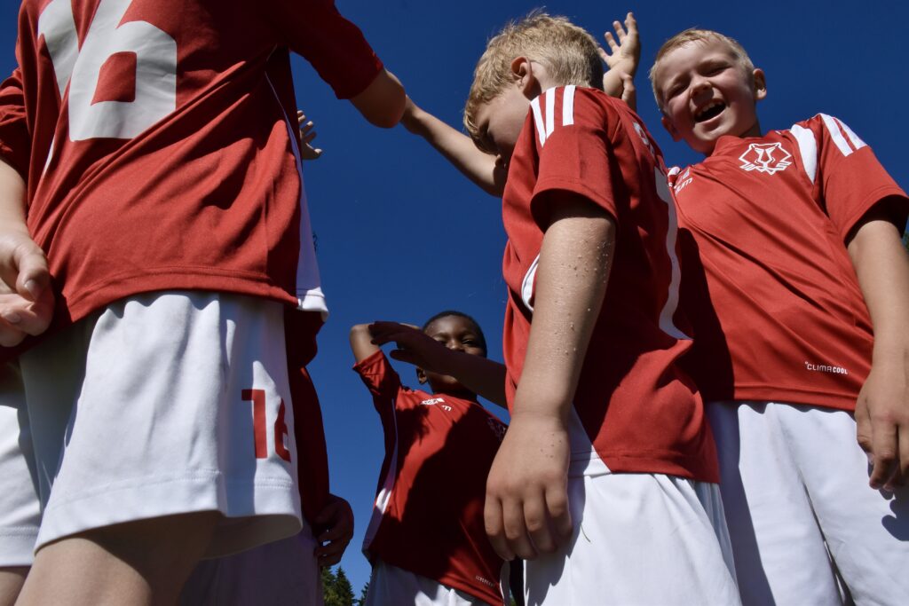 pienet jalkapallojuniorit kannustushuutoa tekemässä
